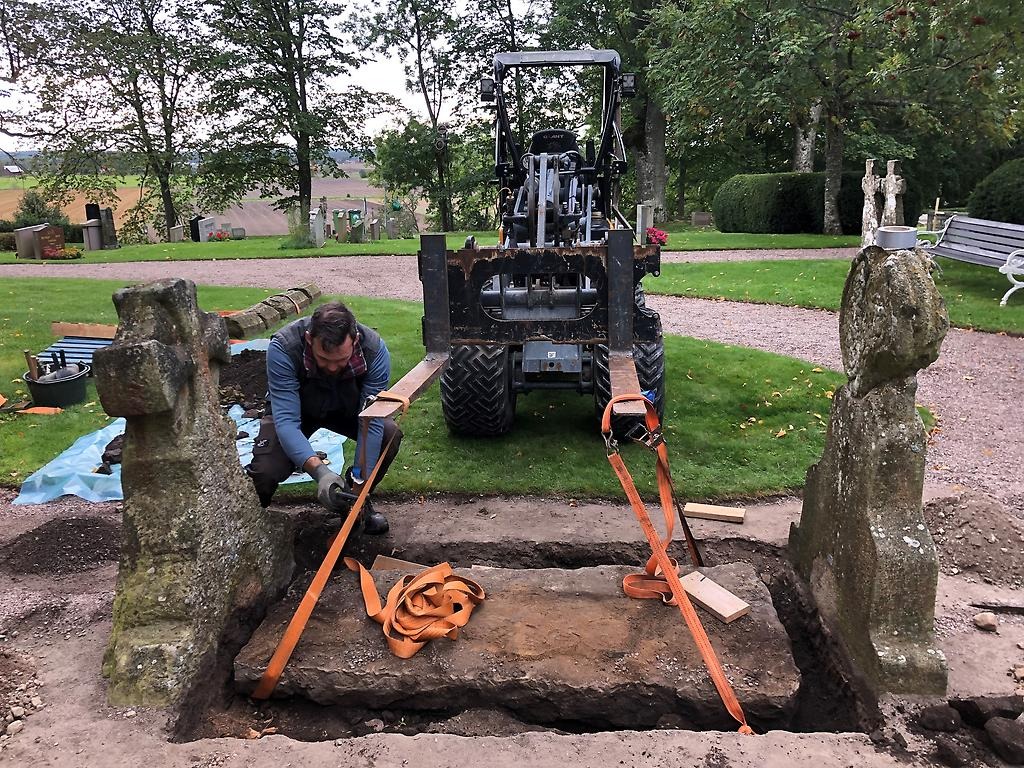 Grav utanför Husaby kyrka öppnas med hjälp av en liten traktor.