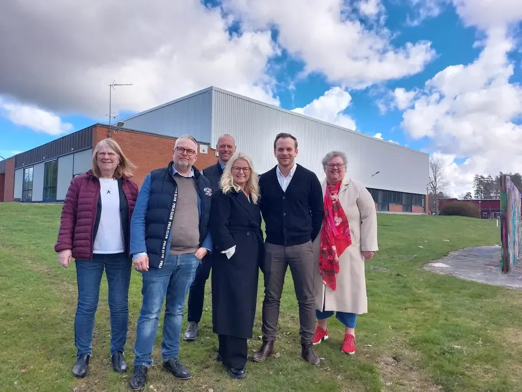 Sex personer framför en byggnad.