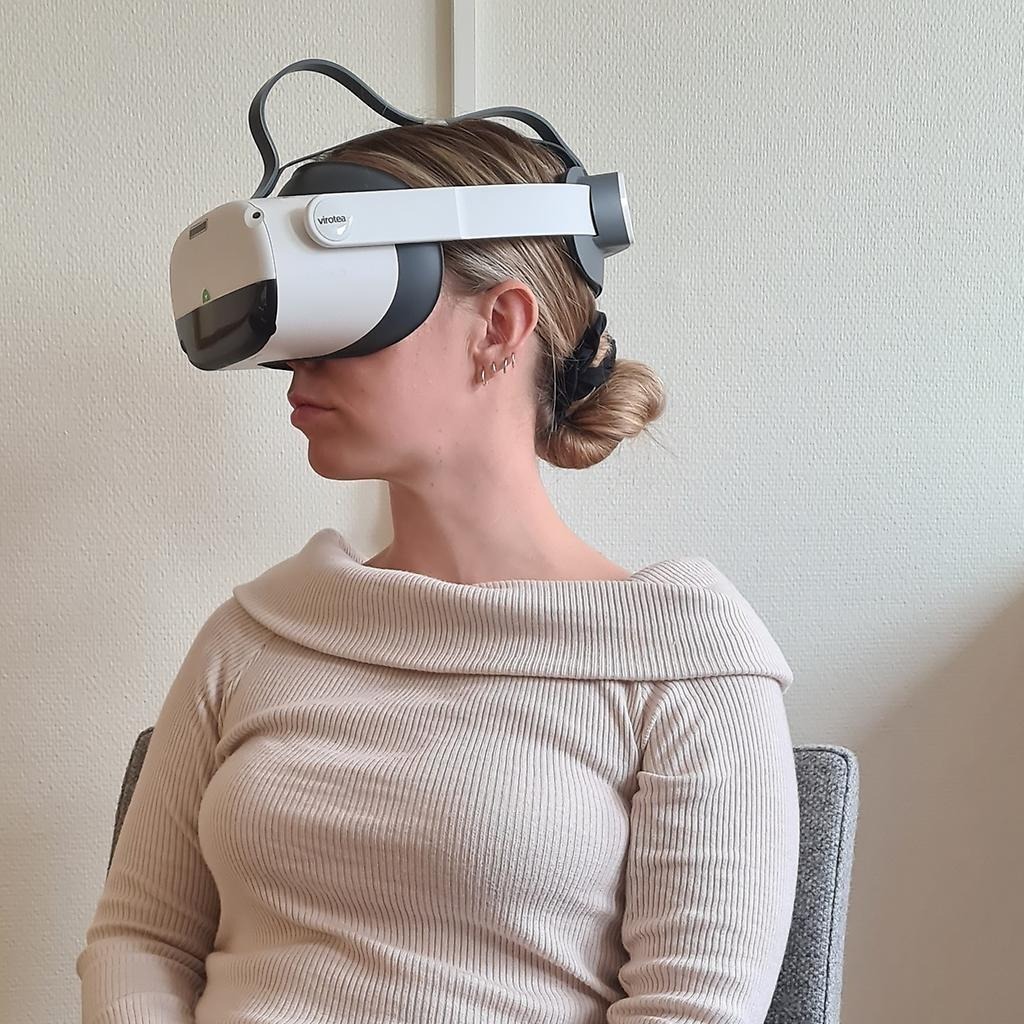 Kvinna sitter i stol med VR-glasögon på sig.