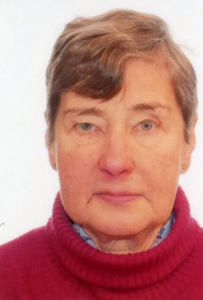 Äldre kvinna med kort hår och röd tröja.