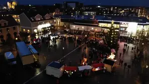 Bild över torget i Götene en mörk kväll taget ovanifrån. Många lampor lyser upp julmarknaden och granen på torget är tänd.