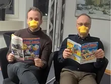 Johan Månsson och Jerker Andersson Liljestrand läser Kalle Anka-tidningar iklädda anknäbbar. 