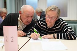 Man och kvinna sitter vid bord med frågesport