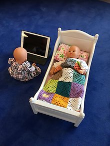 Bild på en sovande docka i en docksäng och en docka som sitter och tittar på en skärm.